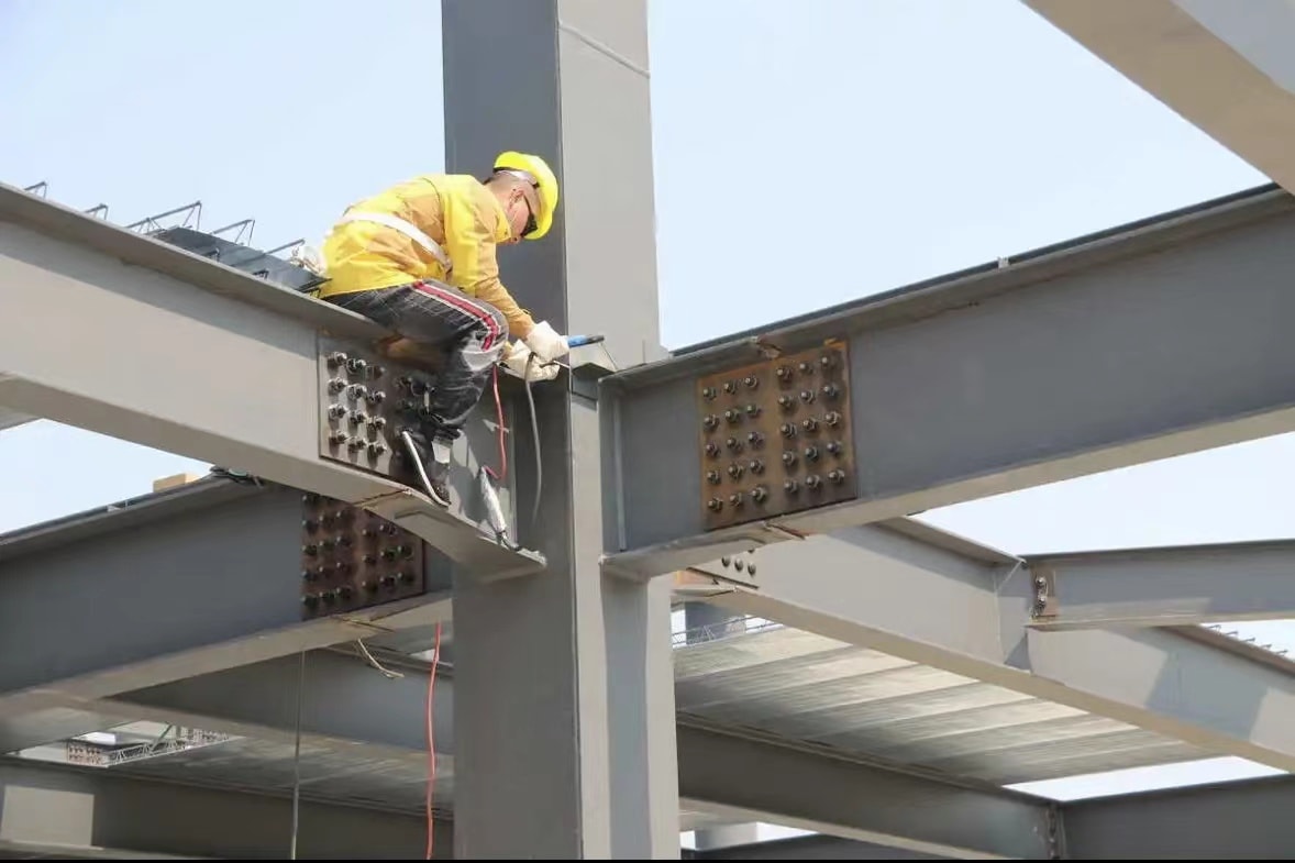 Construction worker assembling bolted structural steel beams on site